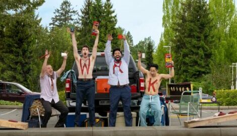Tailgating friends enjoying the football game after work, holding snacks and cheering.