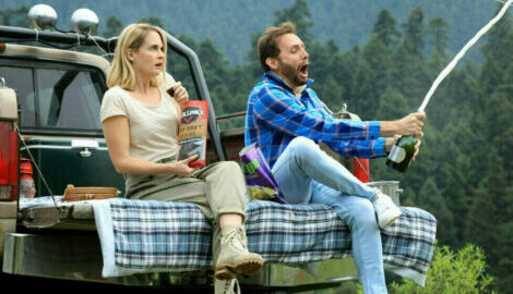 A couple taking a snack break in the woods during a camping trip.
