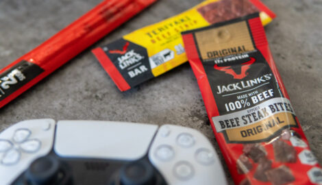 Assorted handheld Jack Link's products laid out on a coffee table alongside a gaming controller.