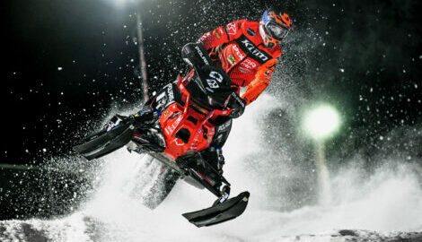 Emil Harr in a mid-air jump with blow blowing in the background during an evening race.