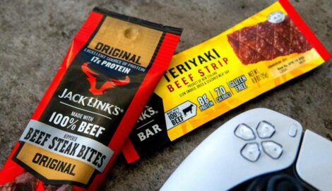 Assorted handheld Jack Link's products laid out on a coffee table alongside a gaming controller.