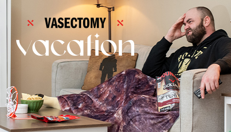 Vasectomy sweepstakes announcement; man sitting on the couch in surgery recovery, snacking on jerky and bundles up with his beef jerky blanket.